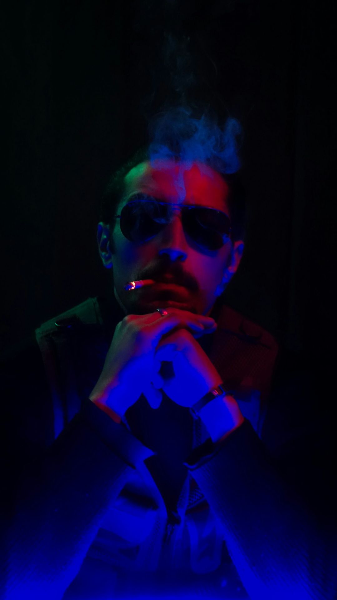 a man wearing sunglasses and smoking a cigarette